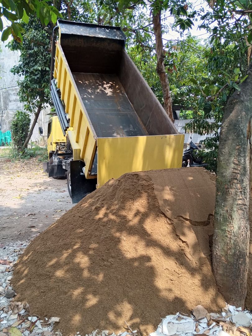 Dump truck menurunkan pasir di lokasi proyek